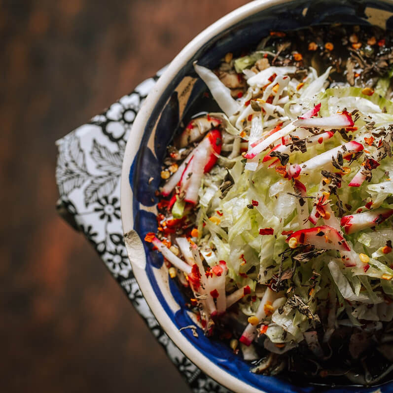 A bowl of Pozole in a white and blue bowl.