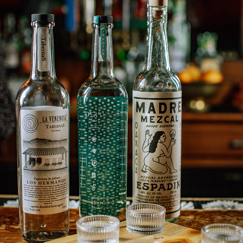 3 bottles of Mexcal on a bartop.